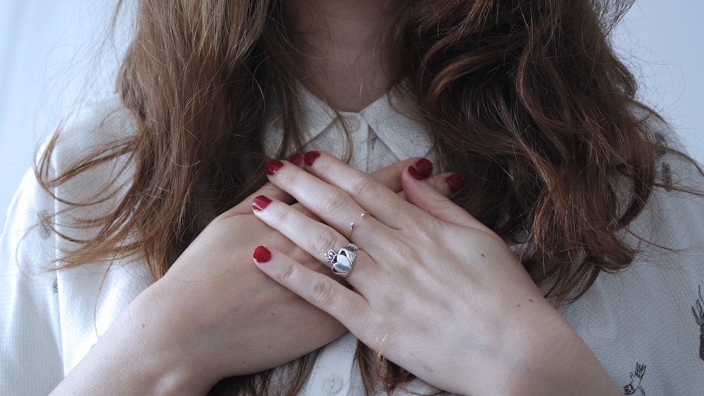 Lady treating herself with self compassion holding her hands over her heart 